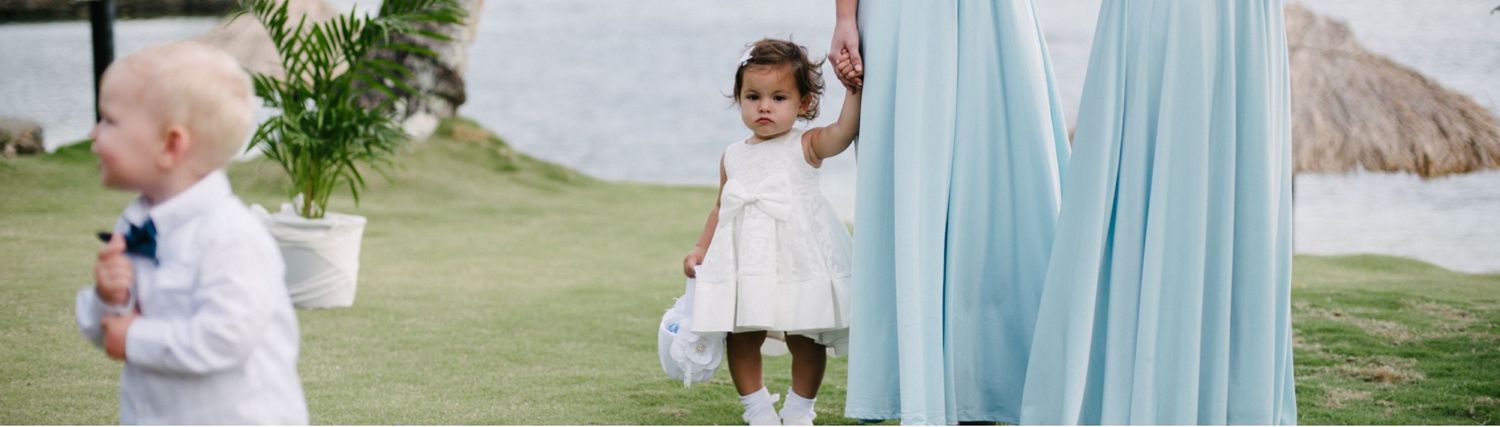 Children in formal attire playing near light blue curtains at an outdoor event.
