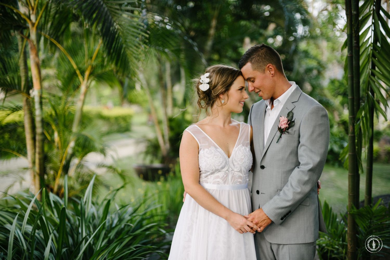 Intimate moment between couple surrounded by lush tropical garden and palm fronds.
