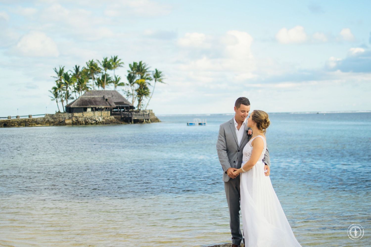 Romantic beachside portrait with ocean and tropical island hut in background.