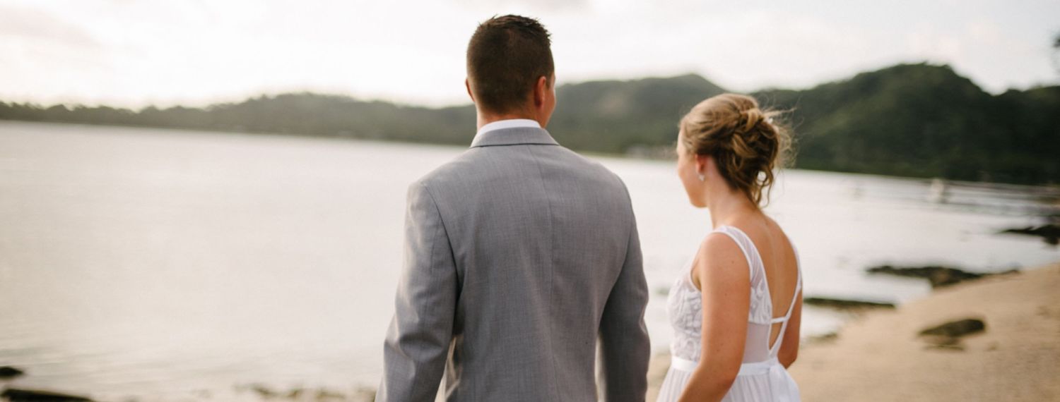 A couple stands overlooking a serene lake view during their wedding day.