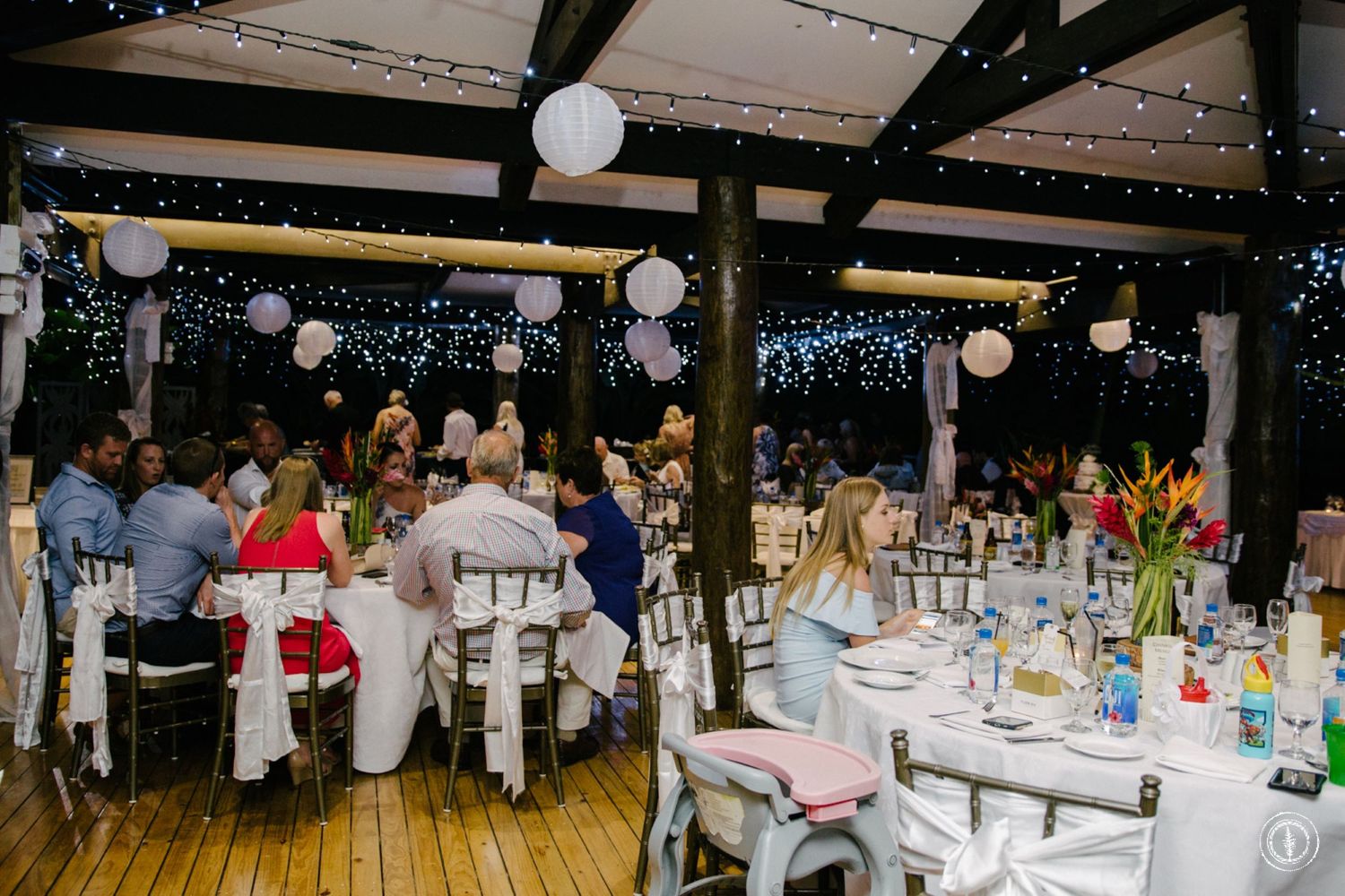 Reception venue with string lights and white paper lanterns creating romantic ambiance.