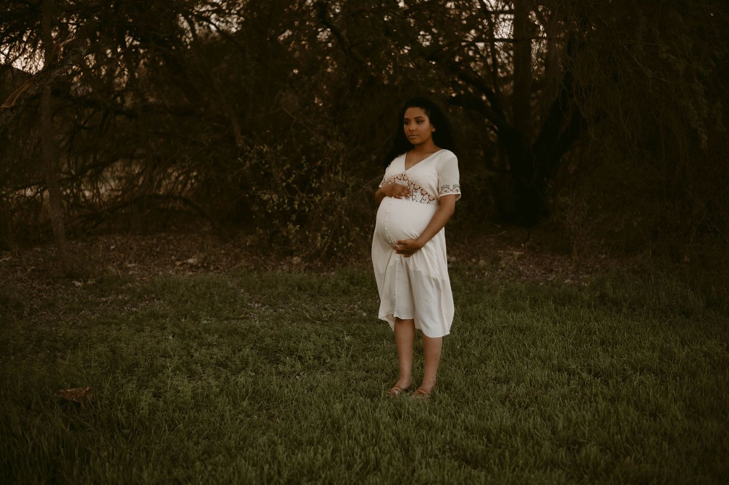 Ethereal maternity portrait in a flowy white dress at golden hour.