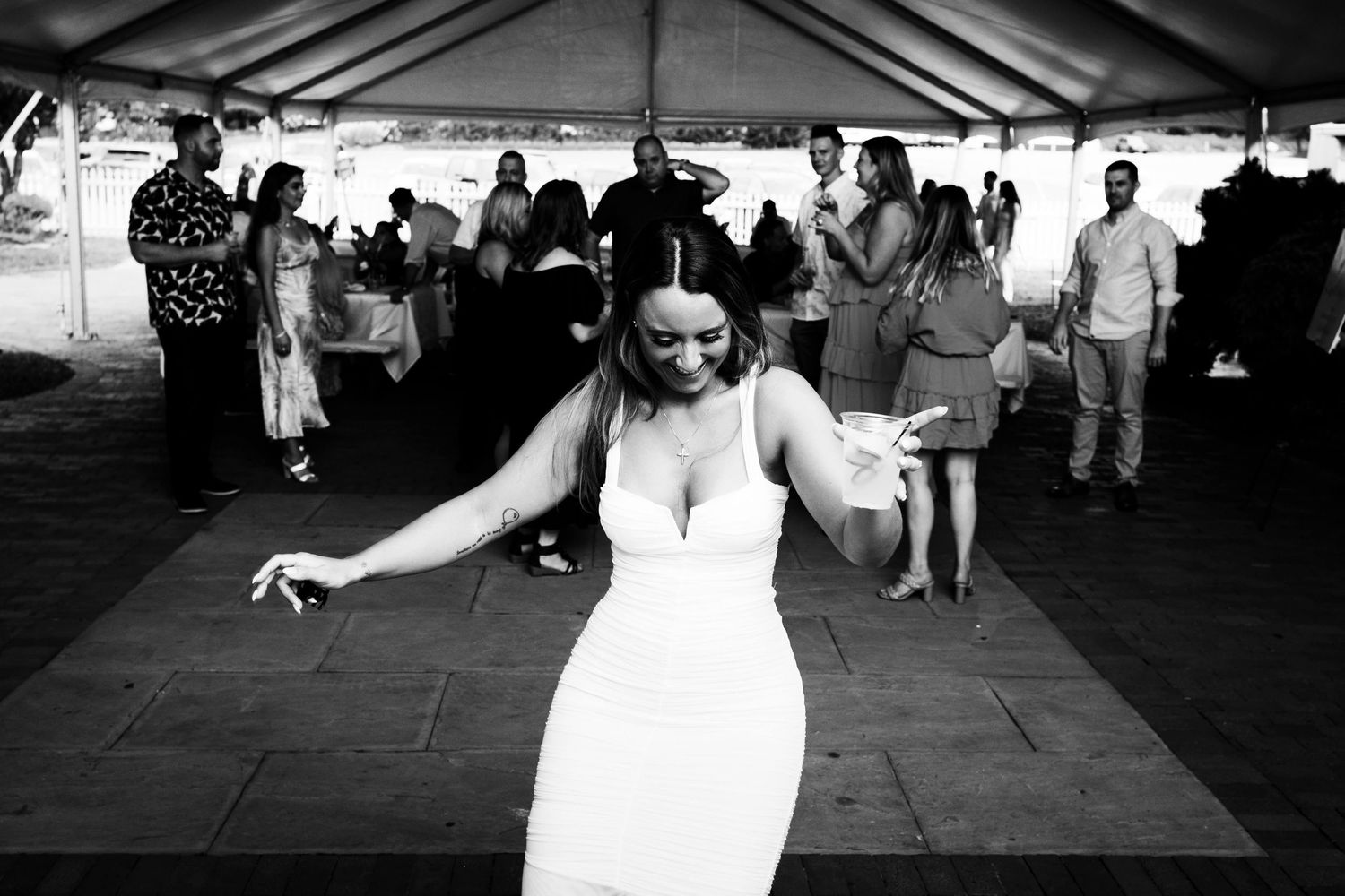A bride dances alone while holding a drink at her engagement party at Milleridge Inn Long Island NY.