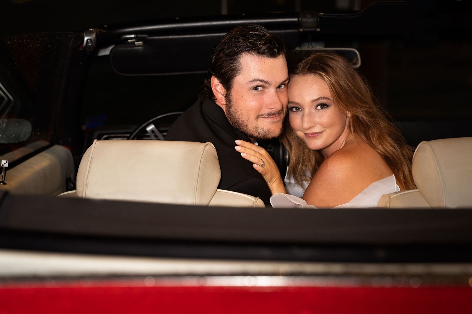 The Historic Pearl parking garage engaged couple sitting in red convertible