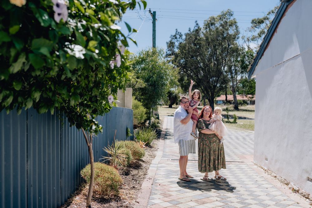 A family with two daughters standing in their driveway during a family photo session