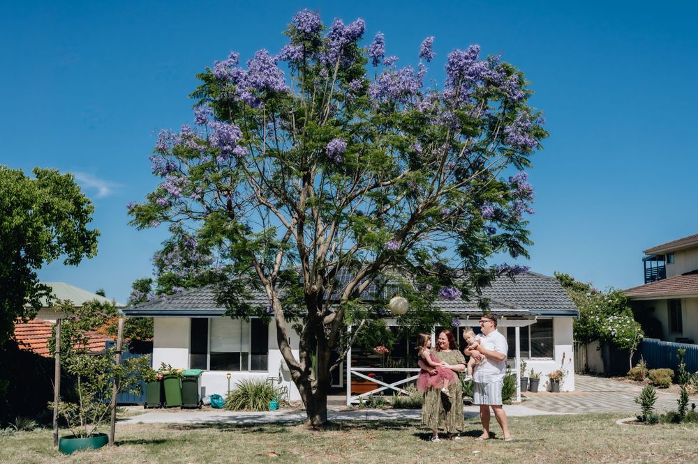 A family with two children standing in front of their family home in Perth