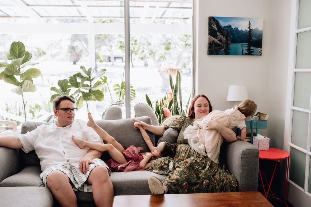 A family relaxed on a couch, with kids climbing on the couch during a family photo session