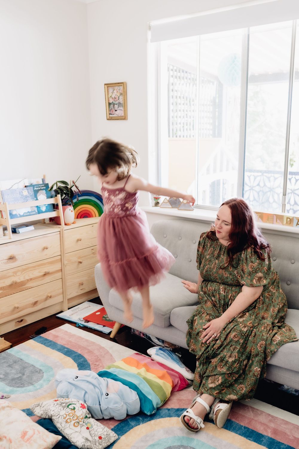 A young girl jumping of a couch in her bedroom at home