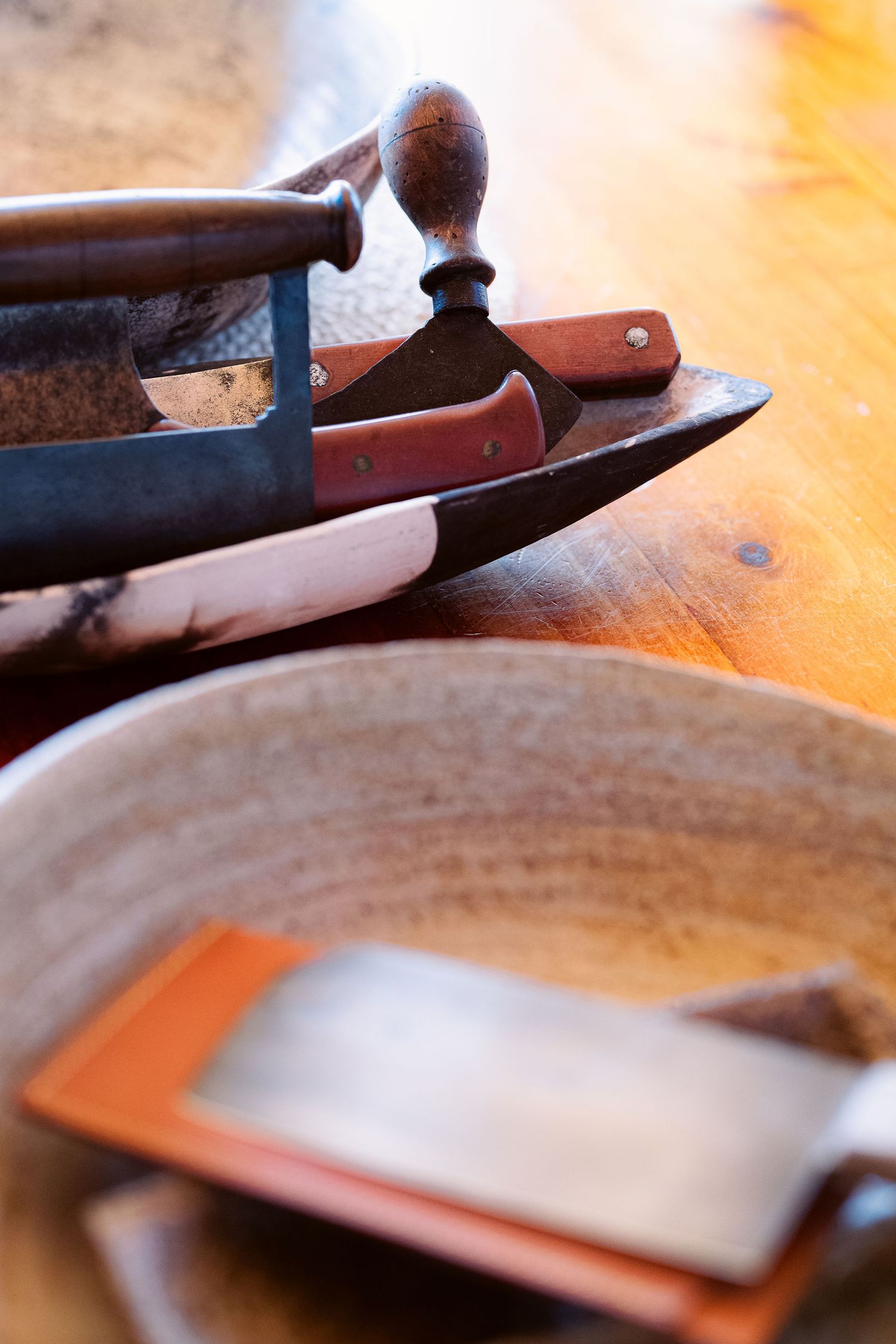 Close-up of kitchen knives and utensils on wooden surface.