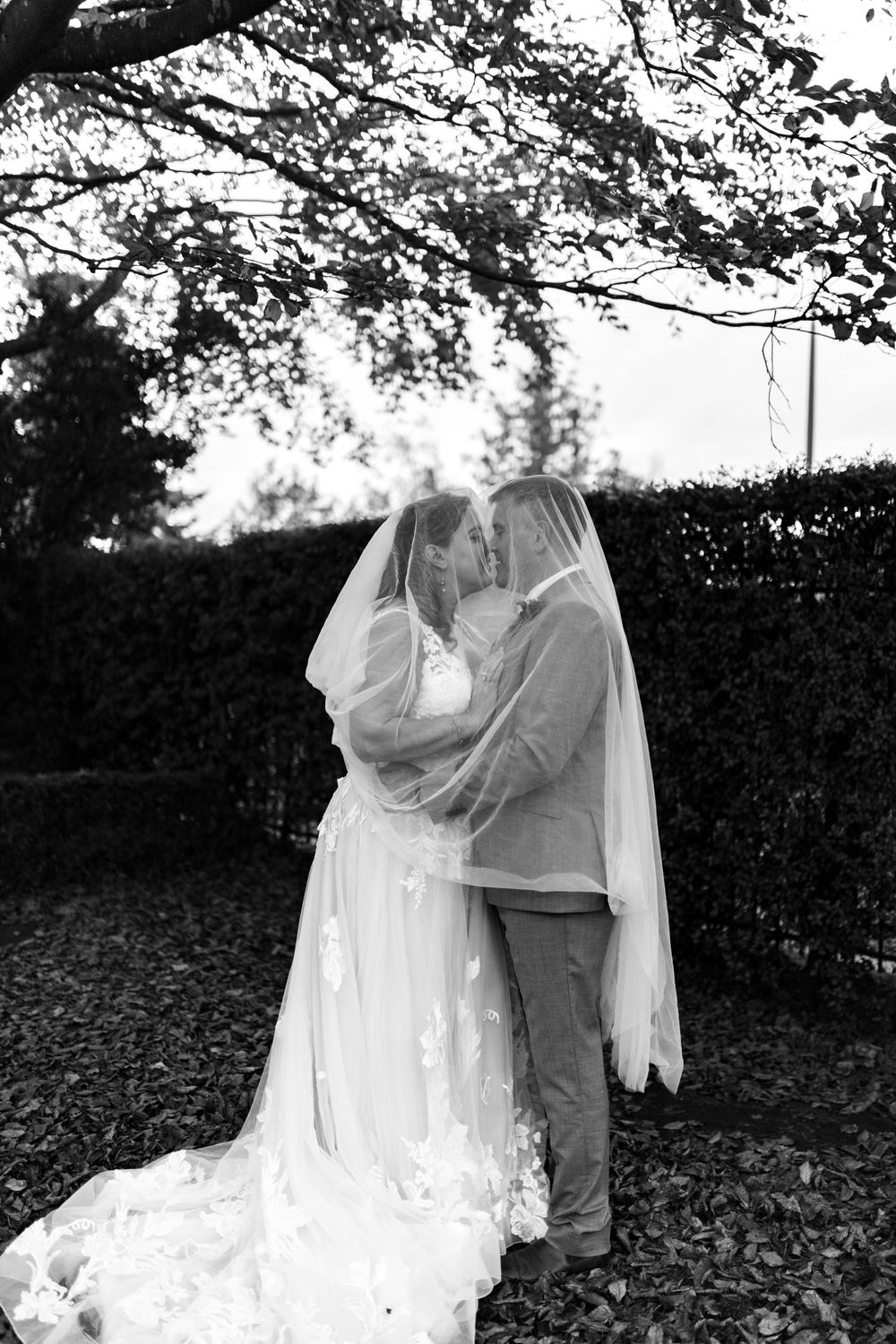 Bride and groom portrait embracing under veils and more veil