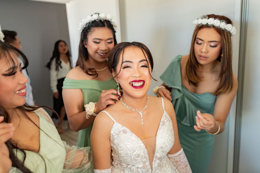 bride surrounded by her bridesmaids putting on her necklace