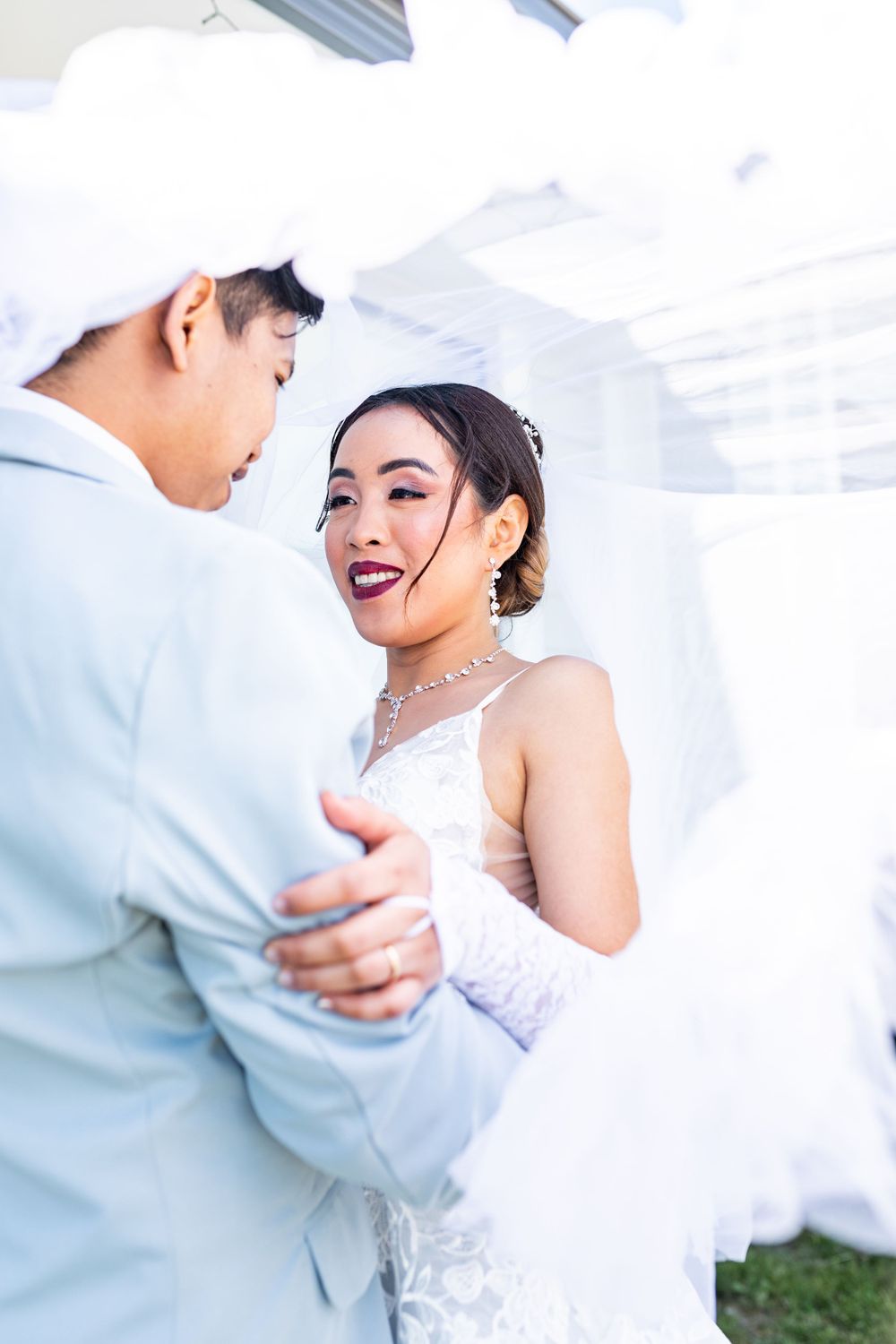 bride and groom with veil over them looking at each other