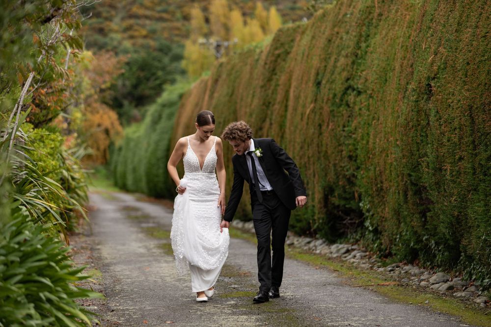 groom holding a brides dress while they walk portait