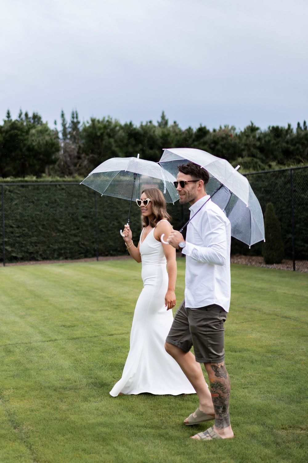 Bride and groom portrait holding clear umbrella while walking