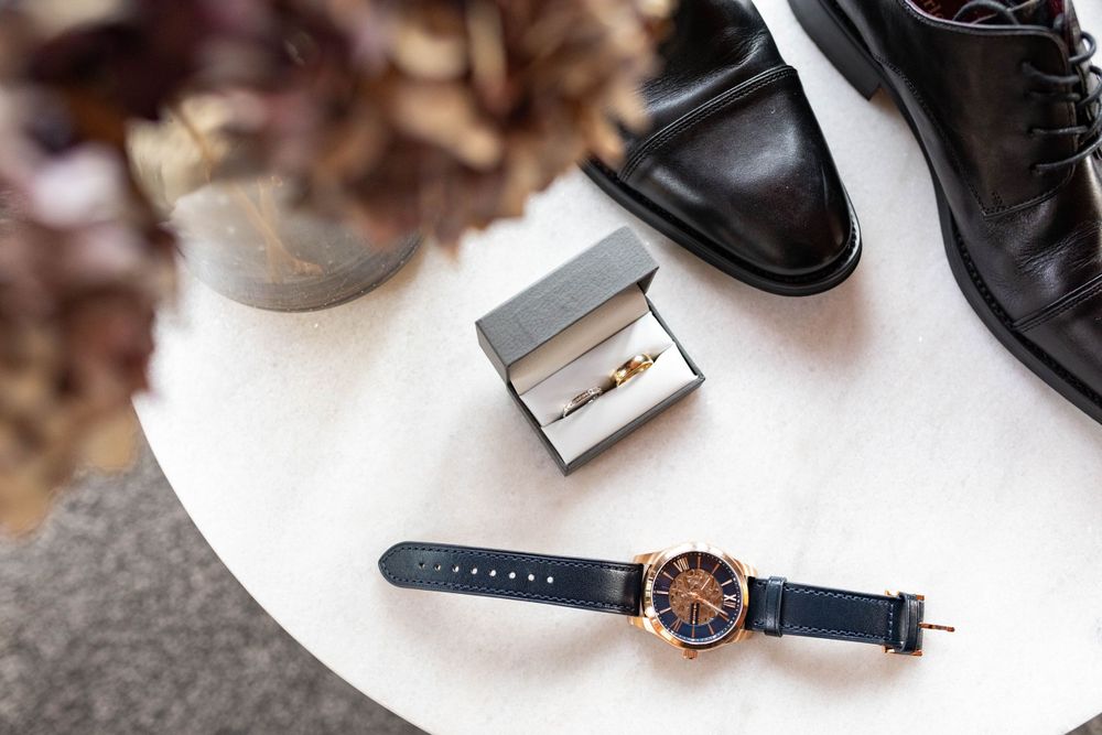 grooms details photograph including watch rings shoes and flowers