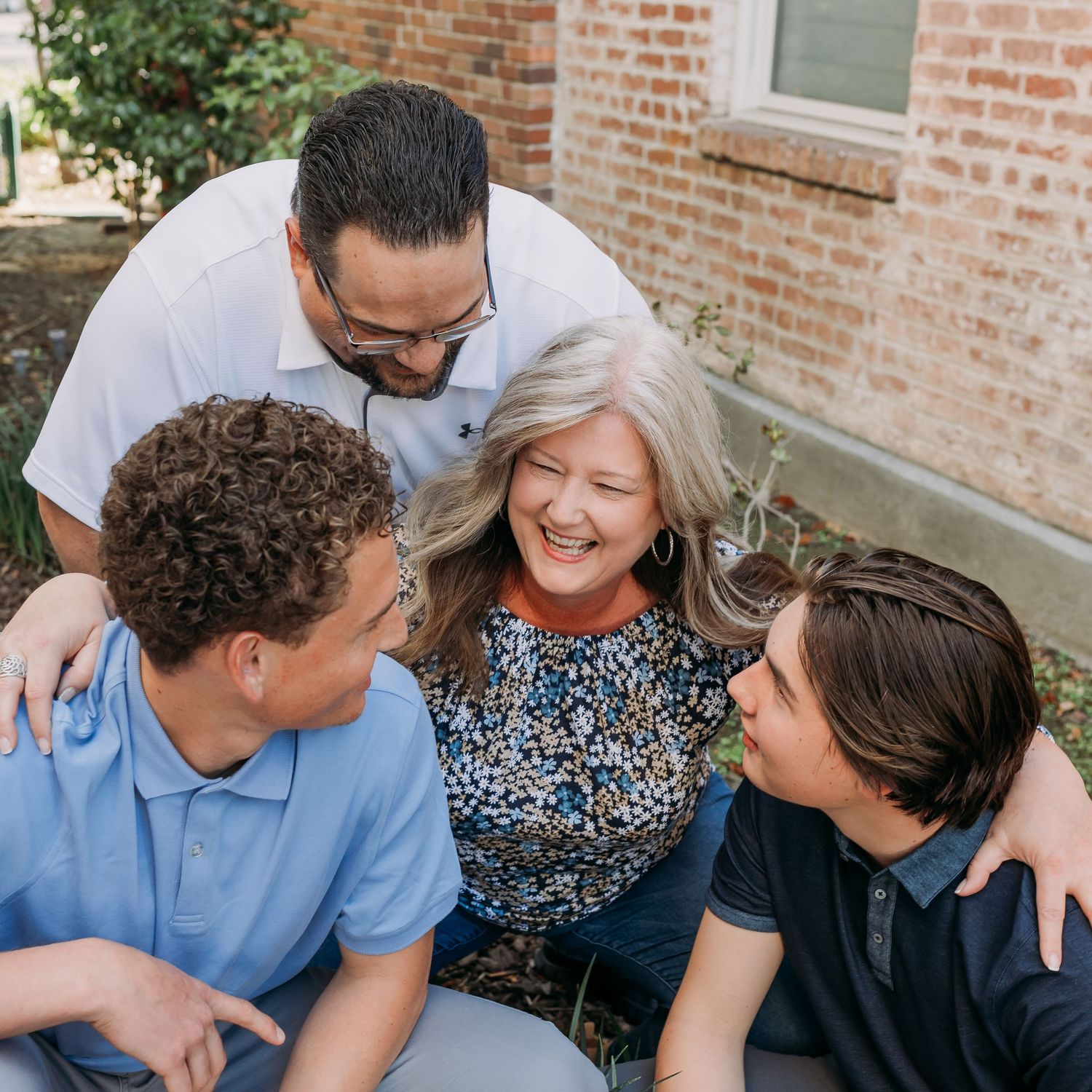 Family pictures with an adult family of four.  Everyone is looking at mom.