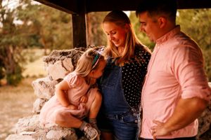 Warm sunset photo of family sharing intimate moment by stone wall.