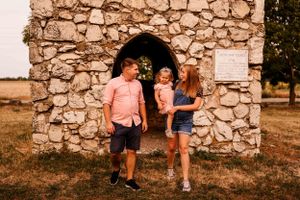 Family poses together inside rustic stone structure during golden hour.