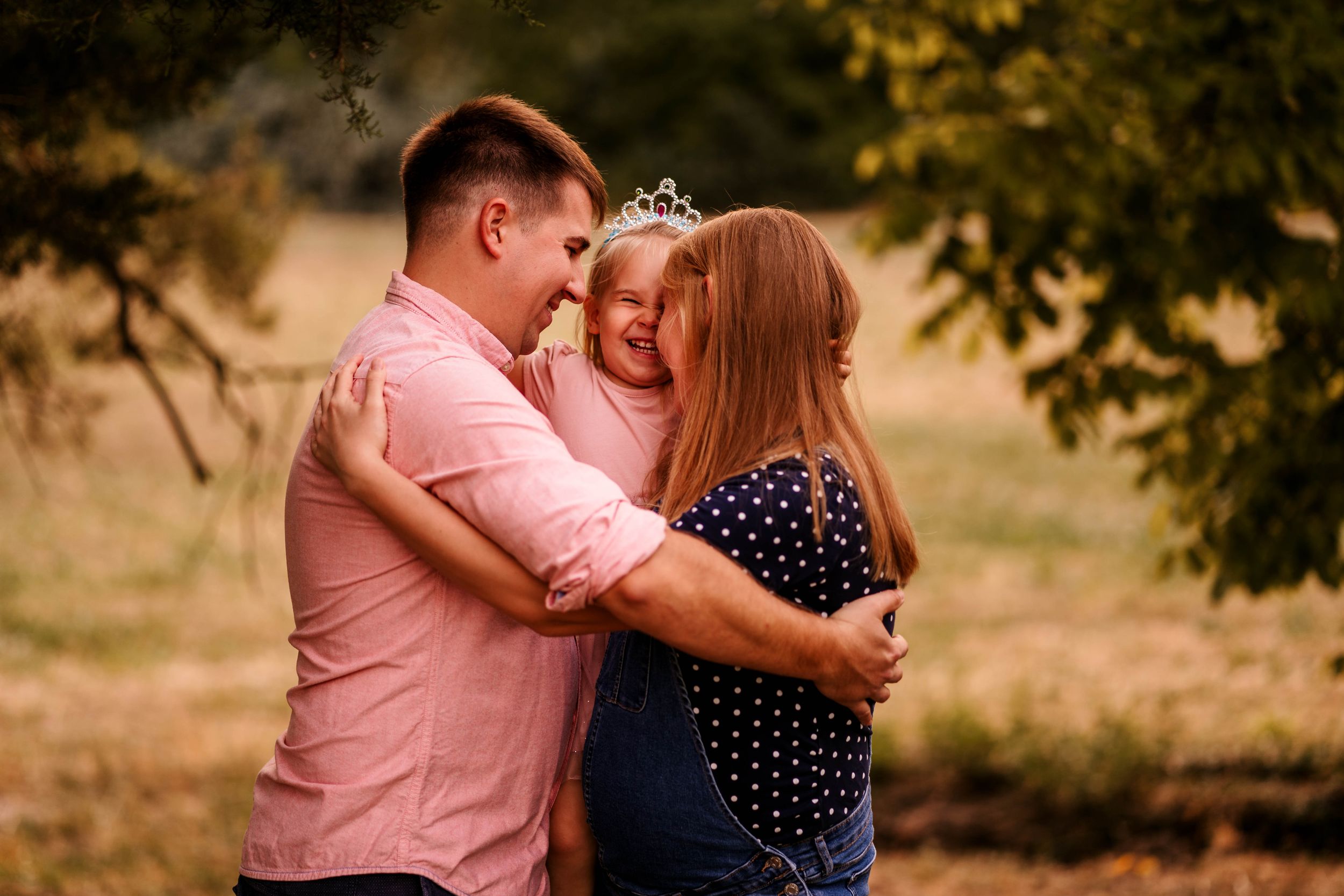 A warm family moment captured in golden light as they embrace in an outdoor setting.
