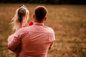 A tender back-view portrait in golden light wearing matching pink and white outfits.