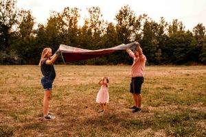 A joyful outdoor scene with a blanket being held up to create a magical play space.