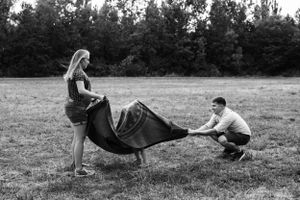 A black and white capture of playful interaction with a blanket in an open field.