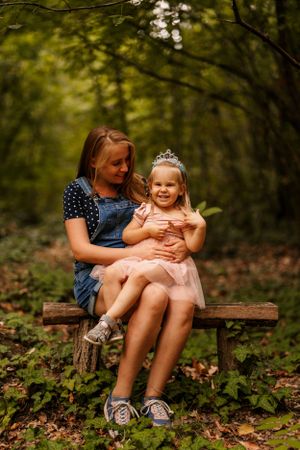 A heartwarming moment shared on a wooden bench in a lush forest setting.