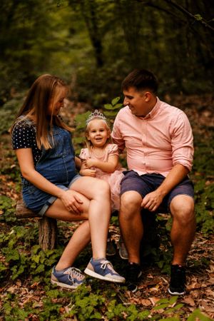 A tender family moment captured on a rustic wooden bench in a forest setting.