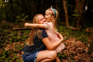 A tender embrace captured in a forested setting with denim and pink clothing.