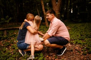 An intimate family moment shared in a wooded setting with autumn leaves.