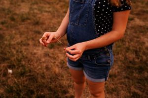 Close-up detail of denim overalls and polka dot shirt in warm lighting.