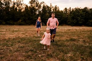 A joyful run through a golden field at sunset with tall trees in the background.