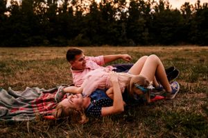 A candid moment of relaxation and happiness on a blanket during golden hour.