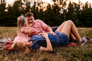 An intimate moment shared on a picnic blanket at sunset with trees in the background.