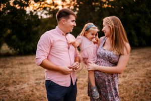 A sweet family moment captured outdoors during golden hour against a warm summer backdrop.