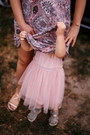 Close-up view of a pink tulle skirt and floral dress against a rustic outdoor background.