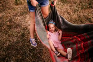 Playful outdoor photography setup with a blanket swing in a rustic field setting.
