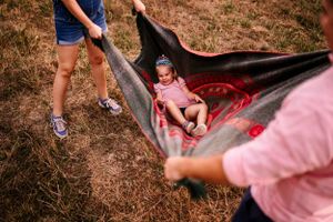 Creative outdoor photo showing a makeshift swing setup with blankets in a field.