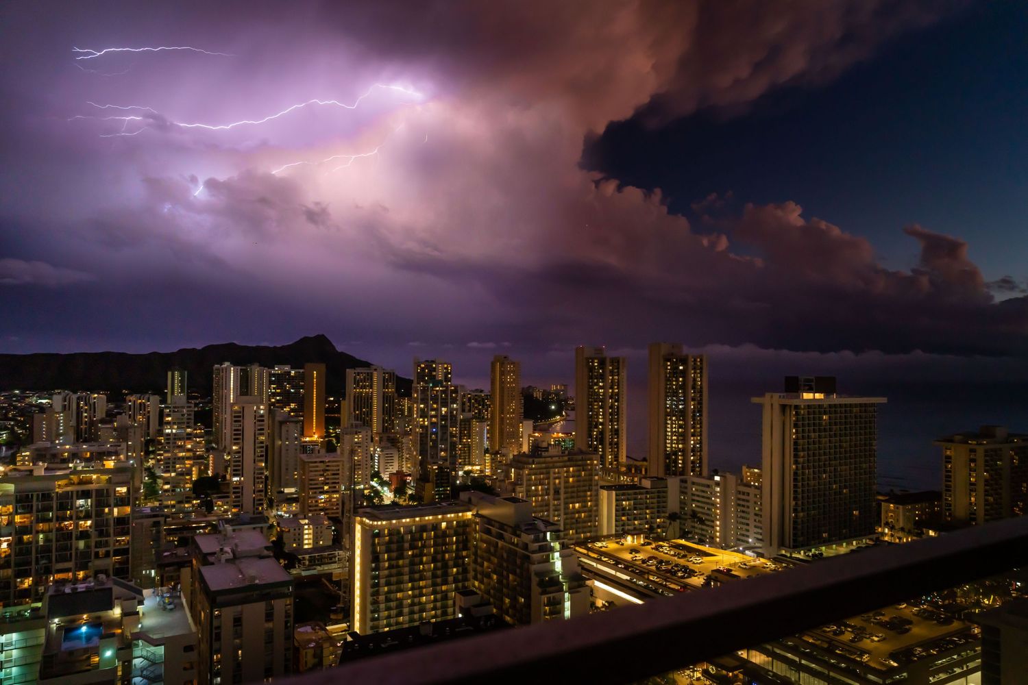 Dramatic purple storm clouds hover over illuminated Waikiki high-rise buildings at twilight. Fine Art Photography