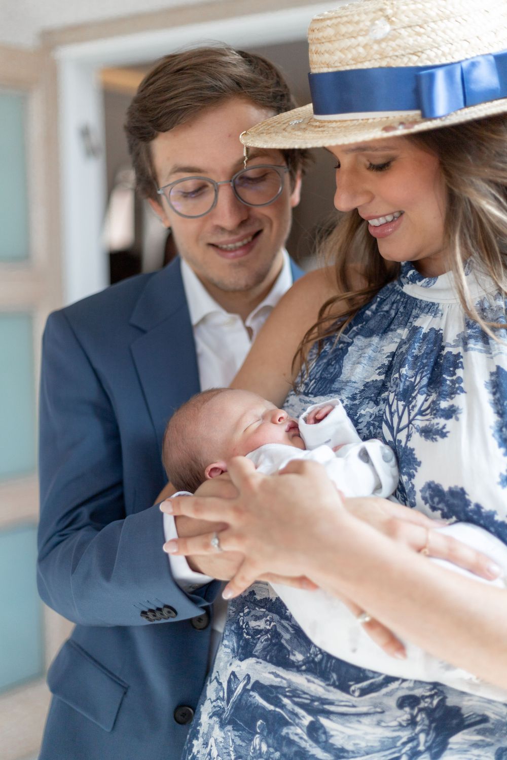 A newborn baby being held while wearing traditional white clothing at a celebration.