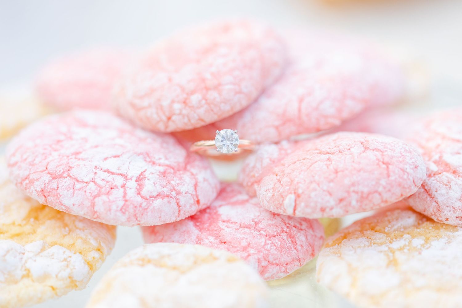 Pink frosted sugar cookies arranged in a delicate pattern on a white surface.