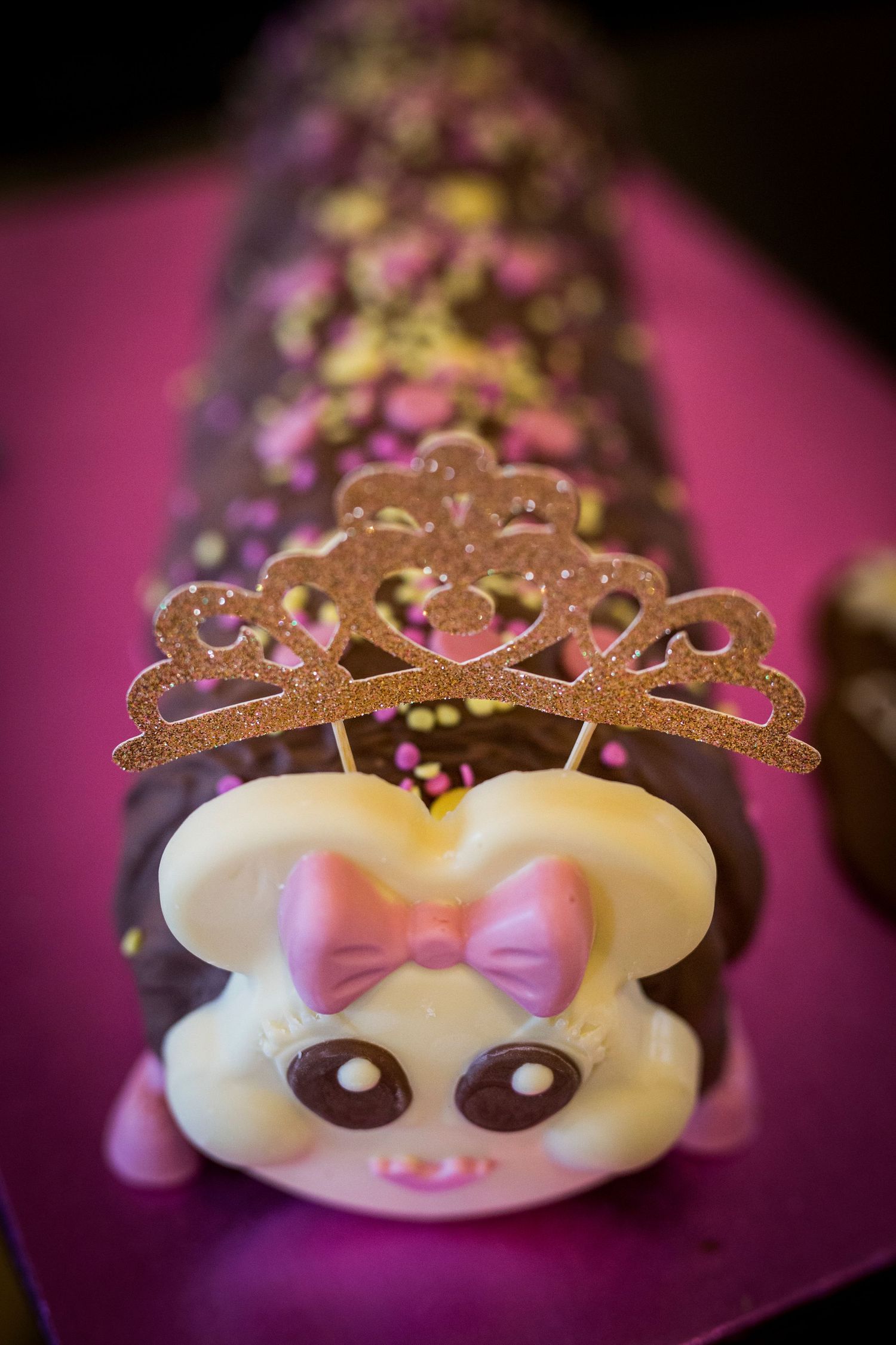 A decorative princess crown sits atop a cute mouse-themed dessert with pink accents.