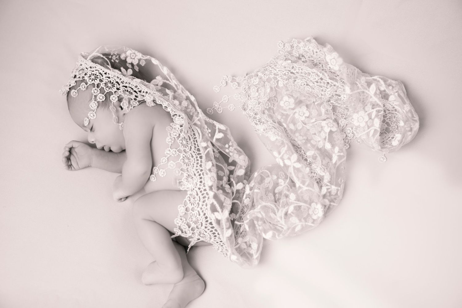 Artistic black and white photo of delicate lace wedding dress details.