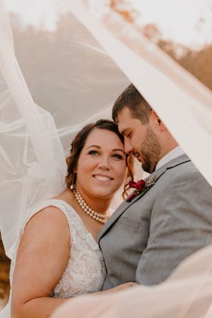 Intimate wedding portrait with flowing white veil and pearl necklace details.