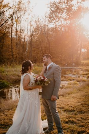 Autumn wedding couple portraits with golden sunlight and natural scenery.