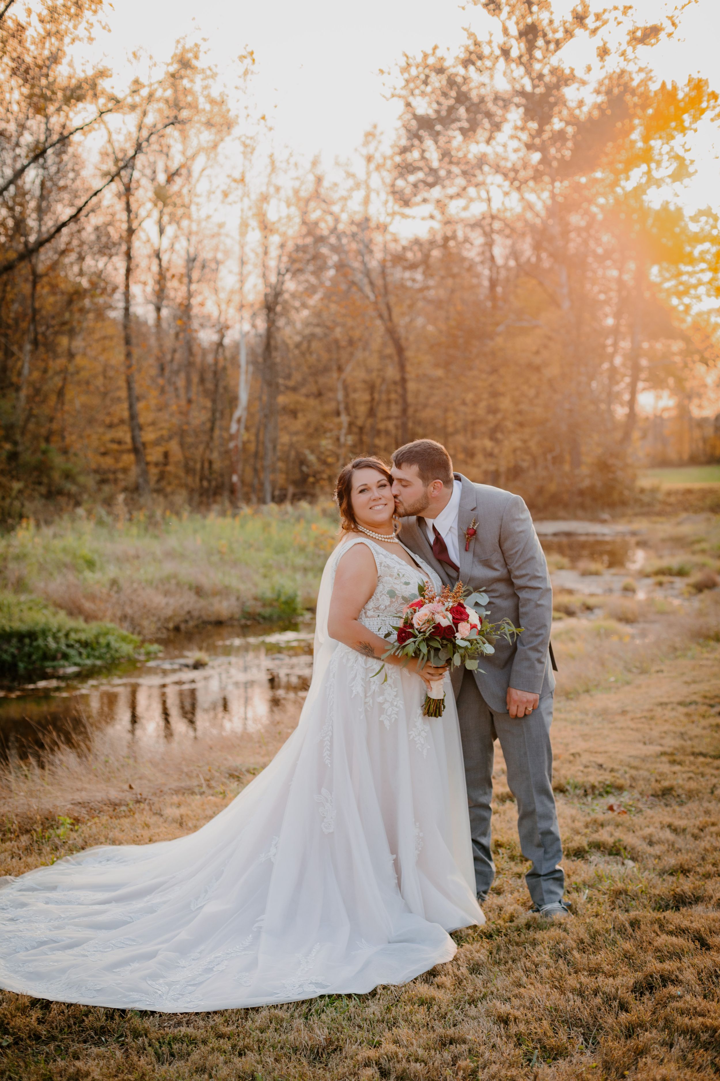 A romantic fall wedding photoshoot featuring a white dress and grey suit against a golden sunset backdrop.