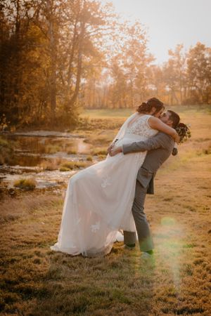 Romantic sunset wedding portraits in golden autumn field setting.