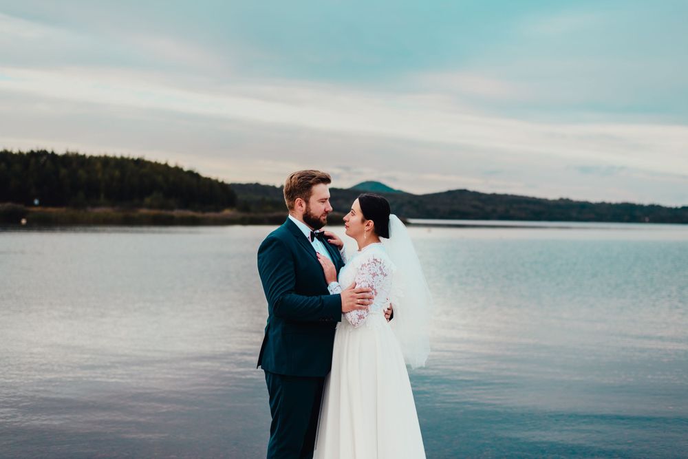 A romantic waterfront wedding photo session with a couple embracing against a serene lake backdrop.