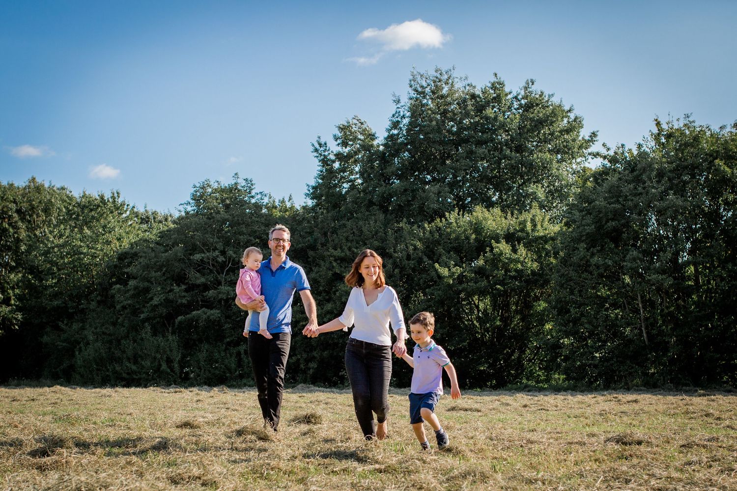 family of four walking across a field in the summer