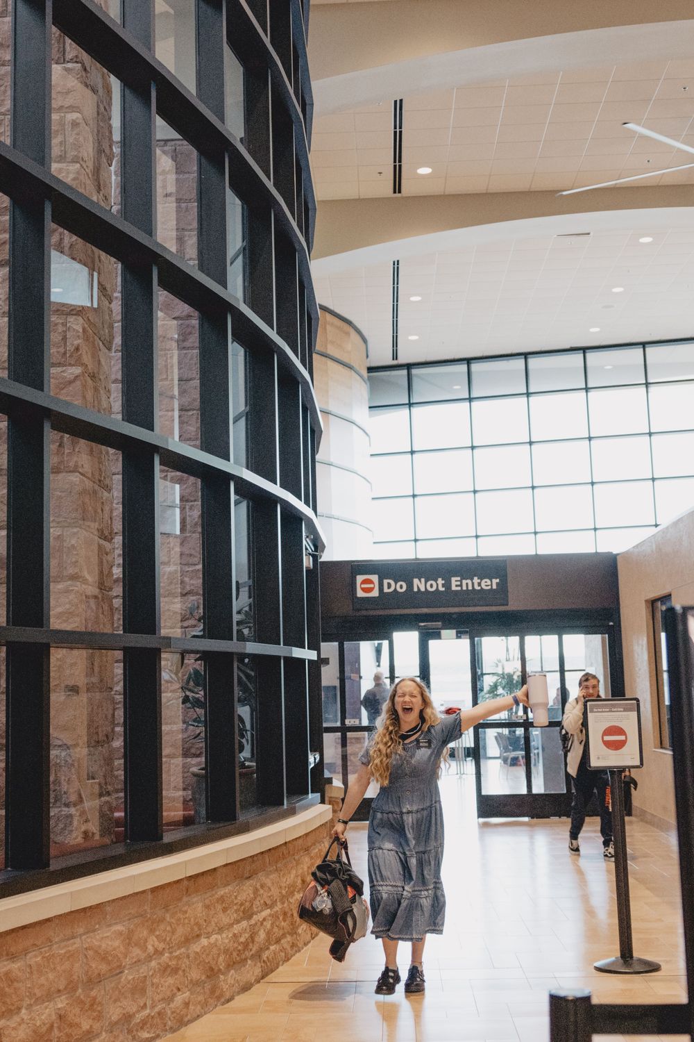 Modern building interior with curved glass wall and 'Do Not Enter' sign in a bright hallway.